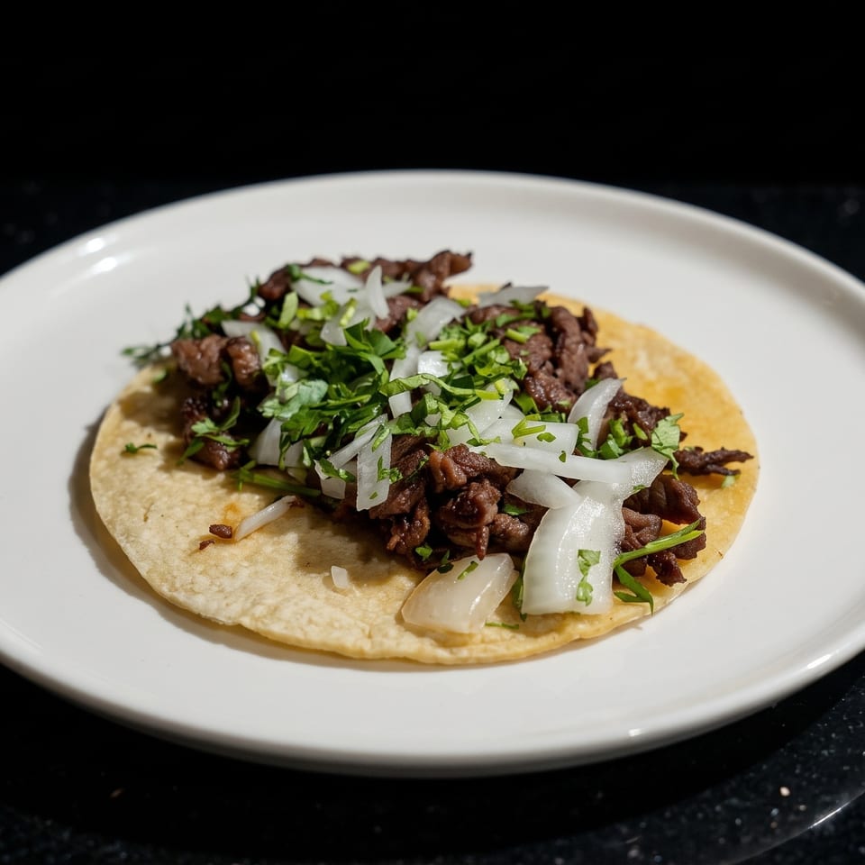 Two soft tacos filled with grilled beef, chopped cilantro, and white onions on a white plate.
